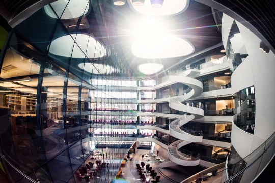 a brightly lit, modern multilevel building on a college campus.