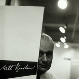 Photograph. Will Burtin at Integration exhibit peaking out from his name plate, shown at A-D Gallery, New York City, 1948. Designed by Burtin. Photograph by Arnold Newman.