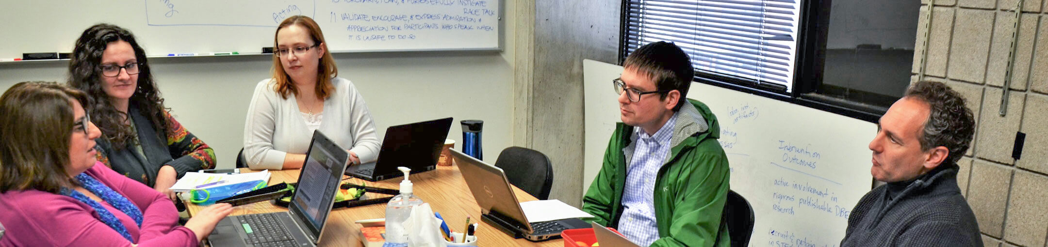 Several R I T faculty sitting at a table, having a discussion.