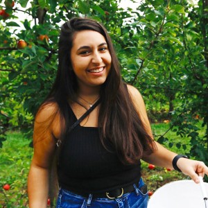 Hannah Spector standing in front of some apple trees.
