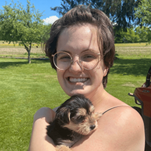 Emma Krofcheck smiling and holding a puppy.