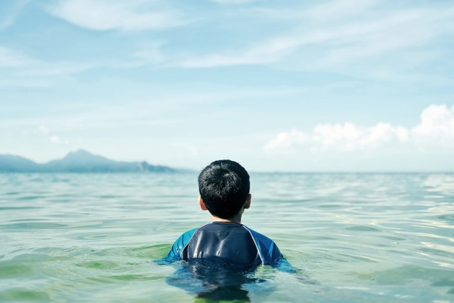 boy swimming in a large body of water.