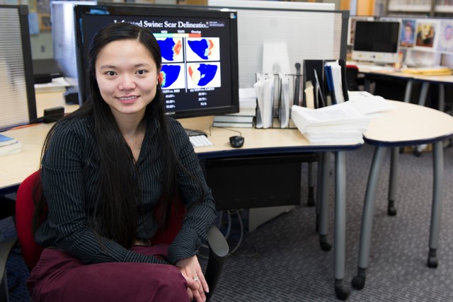 Woman wearing black blouse sits in front of desk with computer.