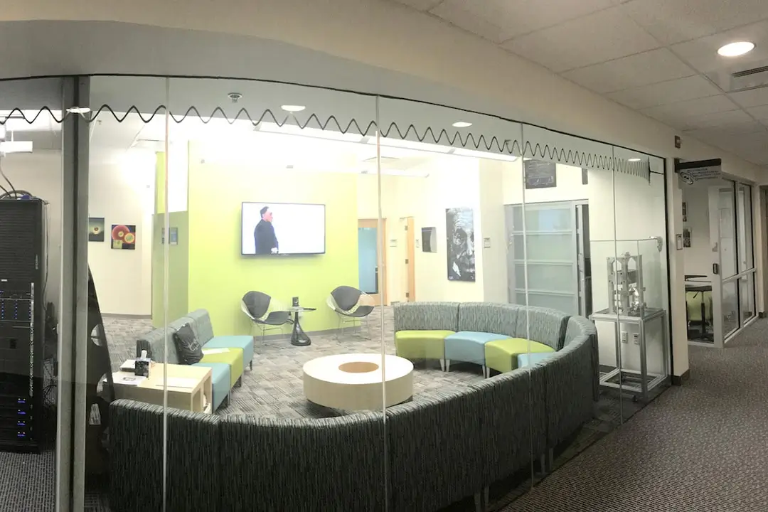 A large lounge space with a modern sectional sofa, round coffee table, and T V mounted to the wall.