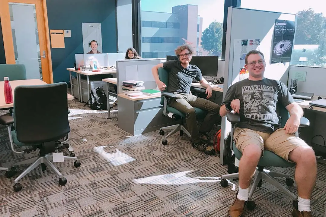 An open-style office space with students seated at work stations.