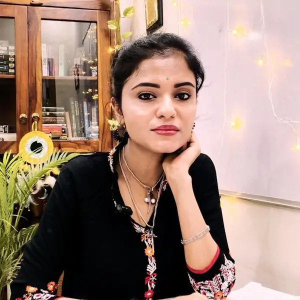 Nandita Sudha Tiwari sitting at a desk, in front of a whiteboard and cabinet.
