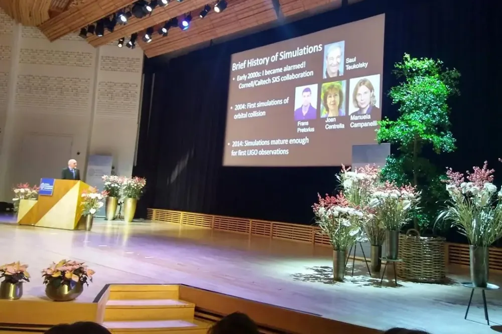 A large stage with a podium and several bouquets of flowers, with information about R I T scientists projected onto a screen.