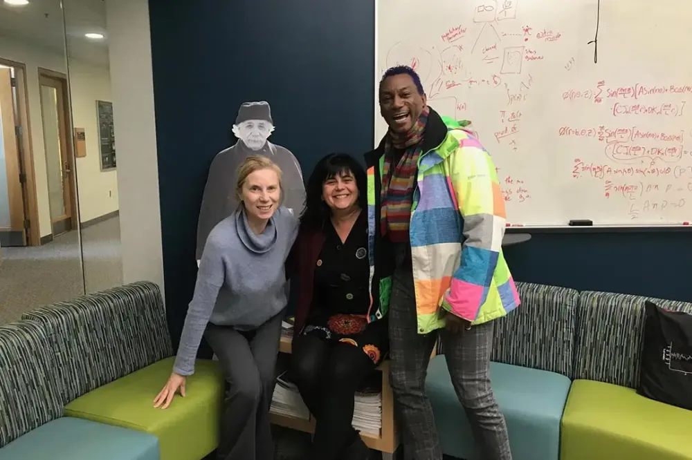 Three people pose for a photo on a sectional sofa.