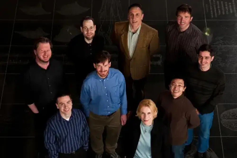 Nine researchers posing for a photo, looking up at the camera.