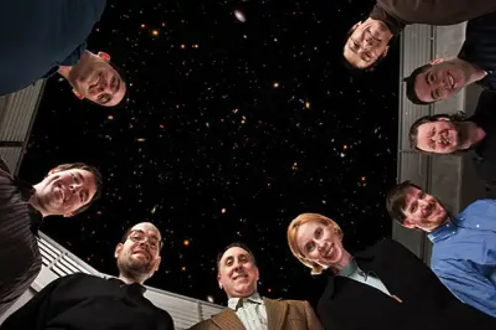 A group of researchers posing for a photo in a circle, looking down at the camera.
