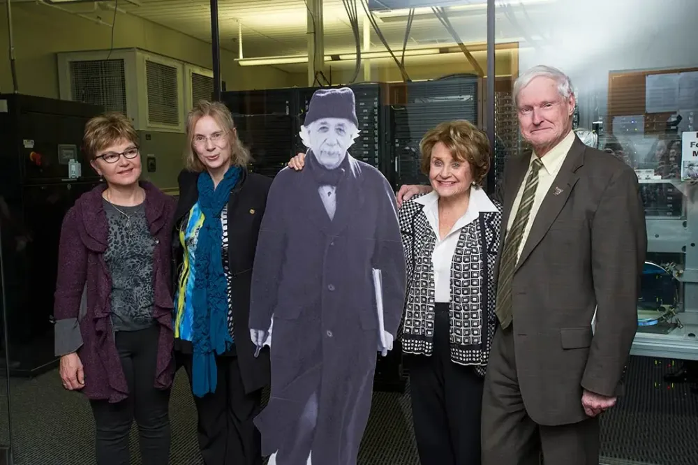 Three people, including a college dean, university president, and local leader pose for a photo with a cardboard cutout of Albert Einstein.