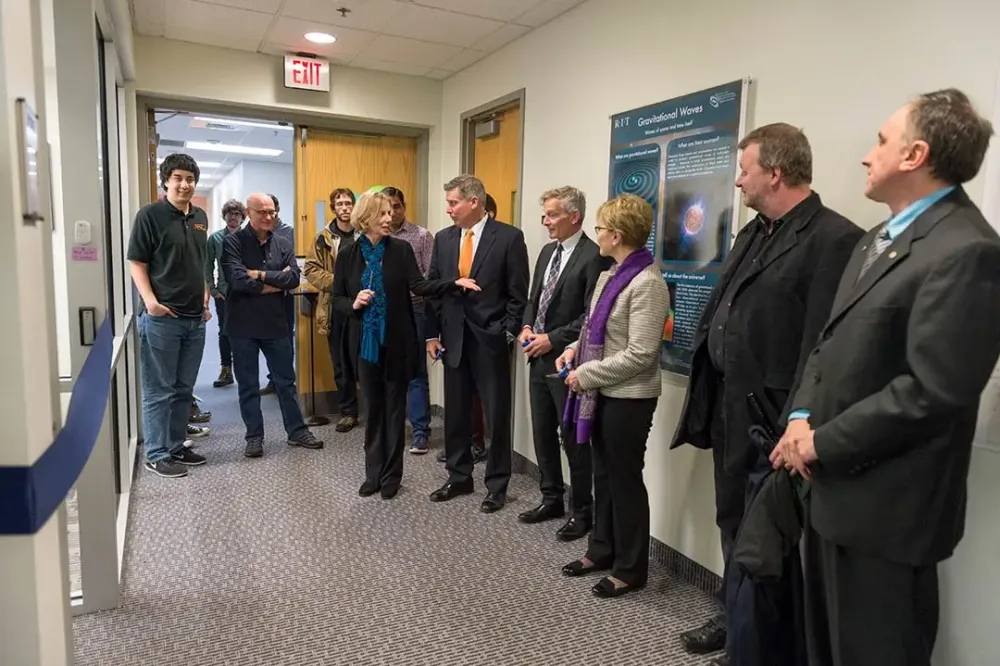 Faculty and staff line a hallway ahead of a ribbon cutting ceremony.