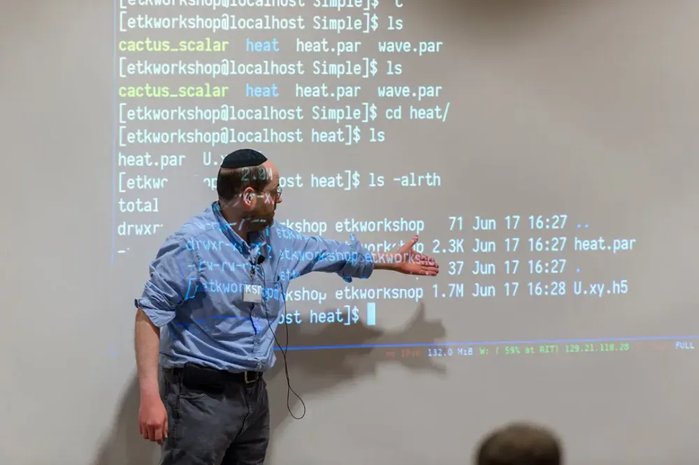 A professor gestures toward a projection showing code.