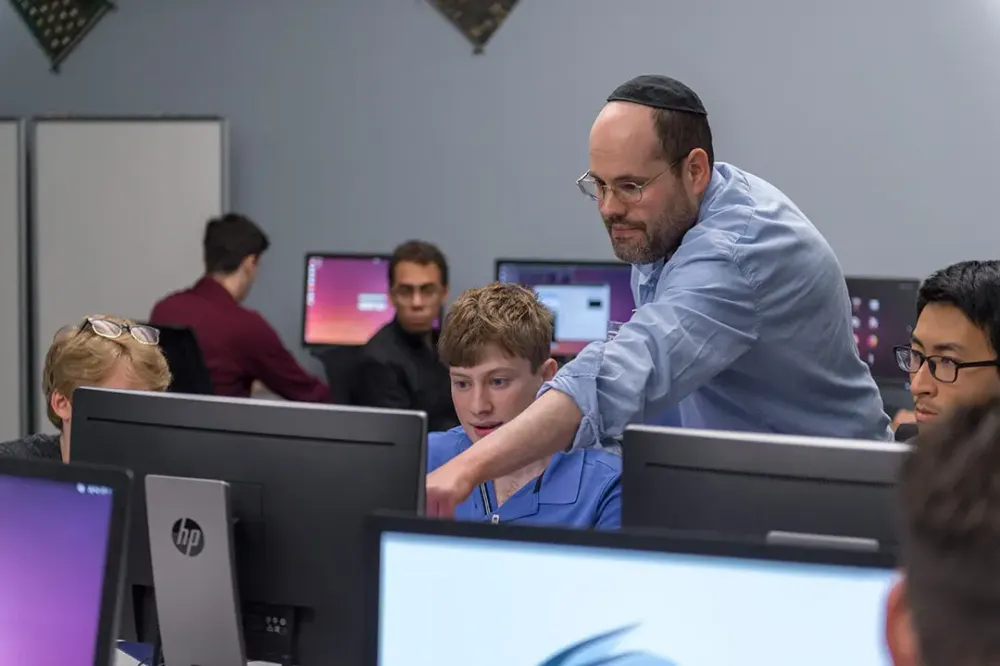 Another view of the professor pointing to a student’s computer.