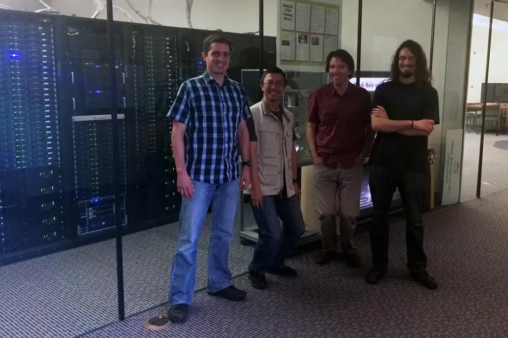 Four researchers pose for a photo in front of a server room.