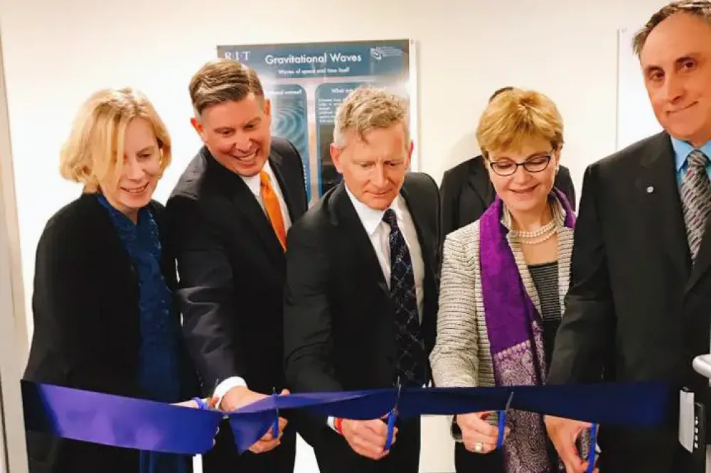 Researchers and university leaders lean forward to cut a giant ceremonial ribbon.