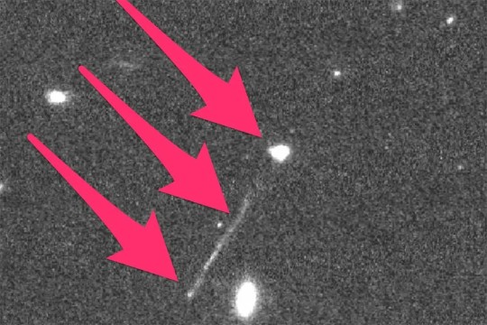image of space with three red arrows pointing to a black hole and a trail of stars.
