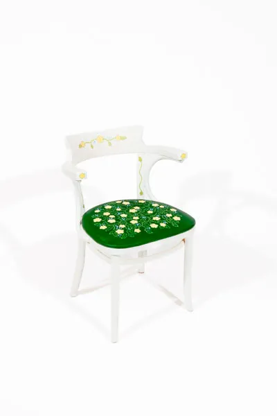 White chair with dark green cushion and floral designs.