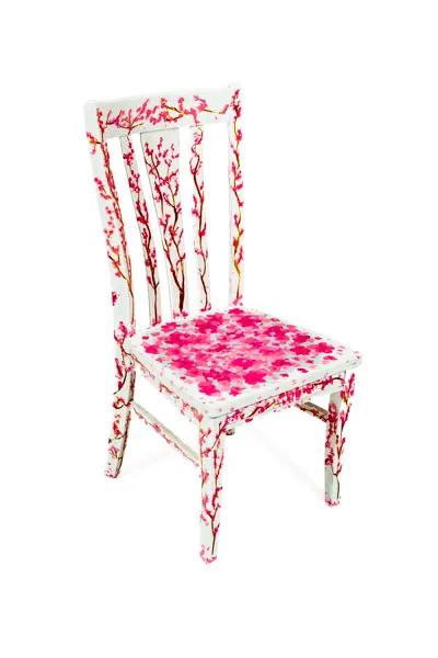 A white chair with branches of pink cherry blossoms