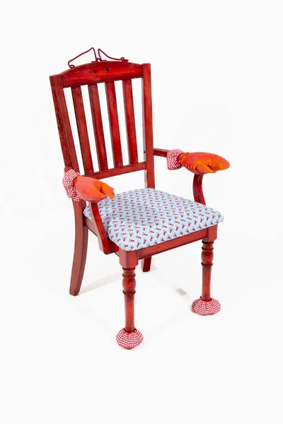 Our chair is wholly themed off lobsters, with gradient on the back to mimic lobster scales, a seat cushion reupholstered with lobster fabric, red and white checkered trim akin to picnic cloth, and lobster claws on the armrests.
