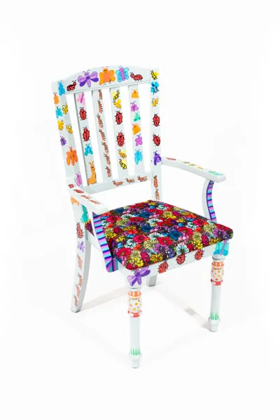 light blue chair with colorful bugs and a bright flower patterned cushion