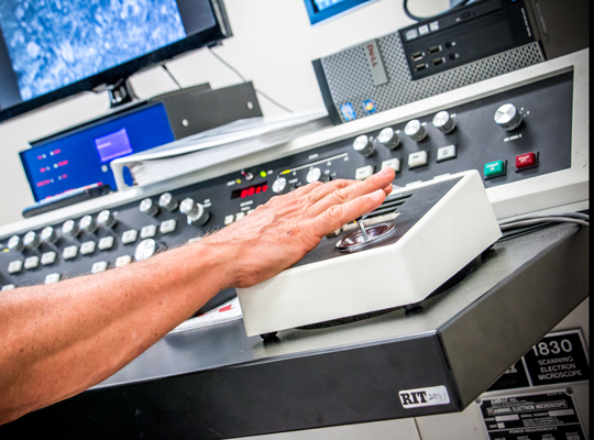 researcher using controls of scanning electron microscope