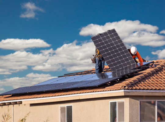 workers installing solar panel on brown roof