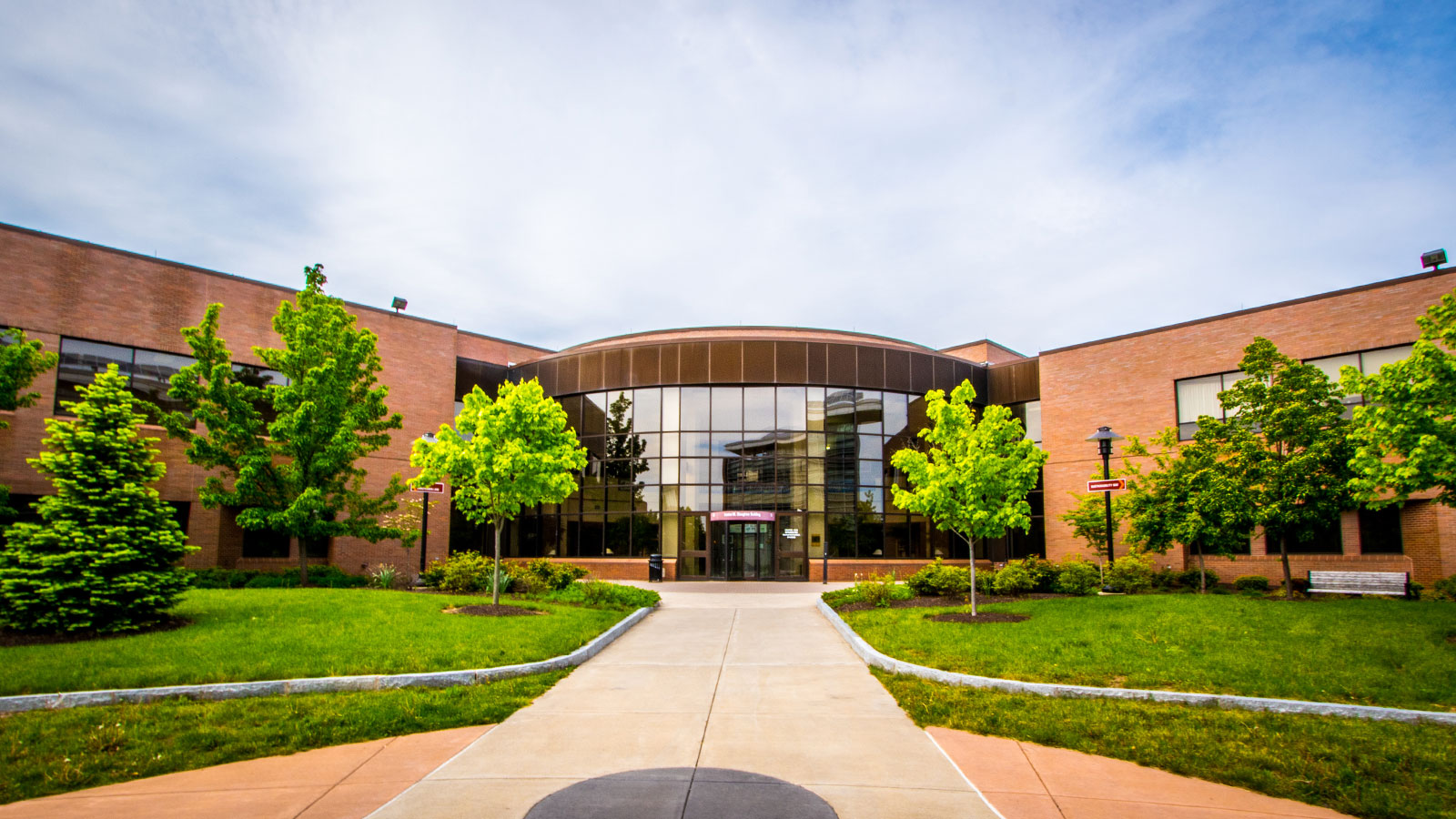 CIMS building exterior with green trees, grass, blue sky, and clouds