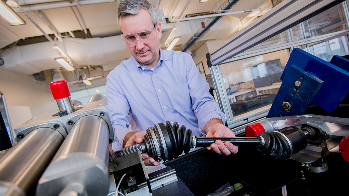 A researcher in a lab handling a mechanical component with precision machinery.