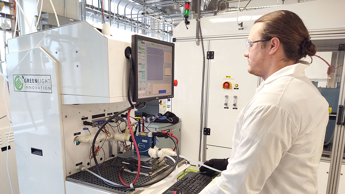 A scientist in a white lab coat analyzing data from an advanced testing system.