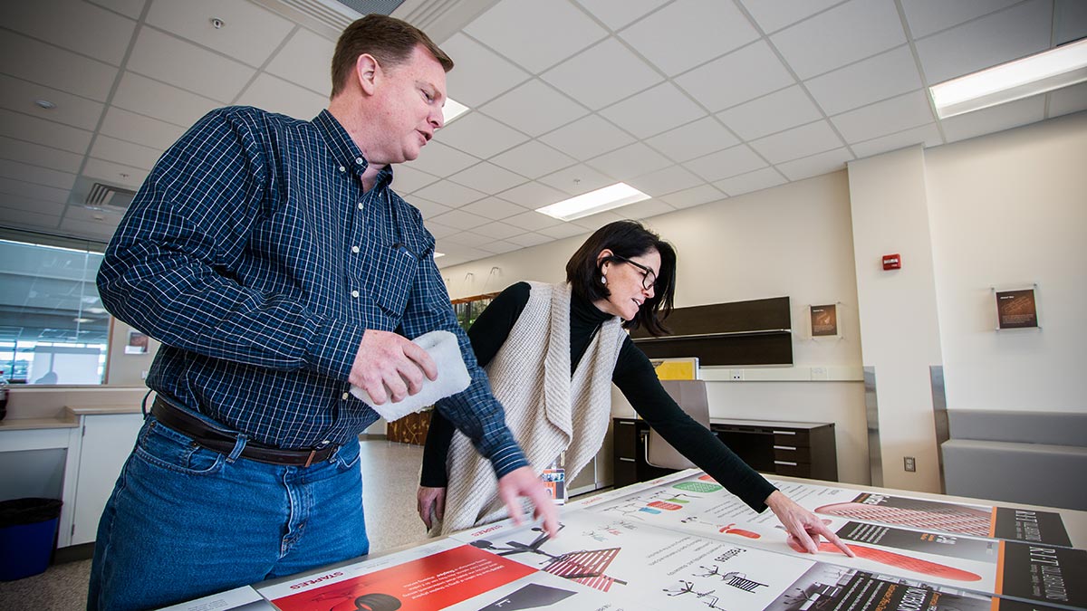 Two professionals reviewing and discussing posters.