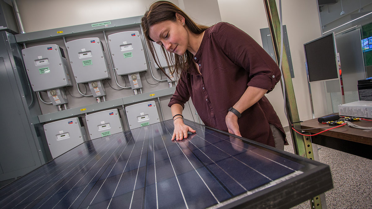 A woman examining a solar panel in a research facility.