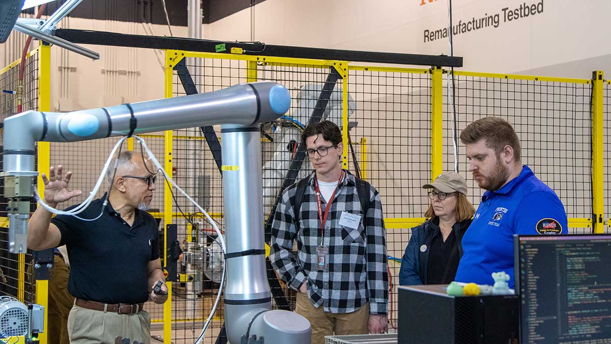 researcher explaining robotic arm to three people.