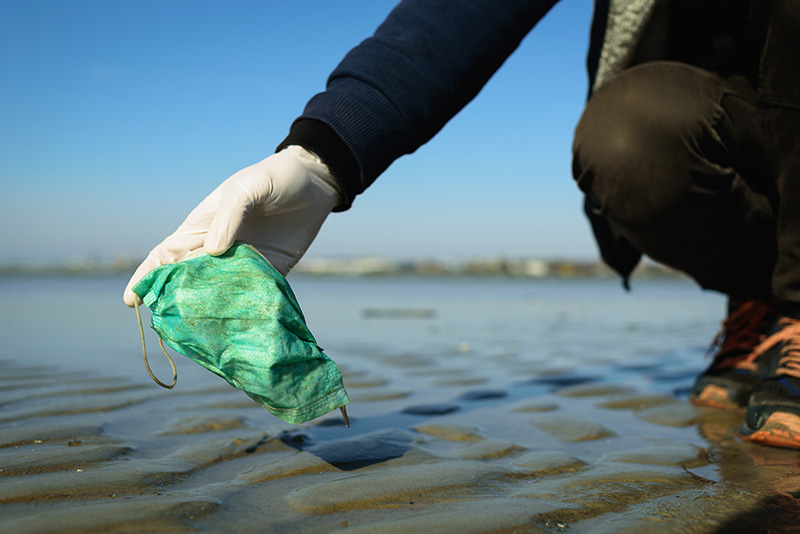 Person lifting mask from beach