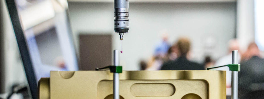 A piece of remanufacturing equipment in the foreground with conference attendees in the background