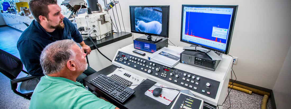 Two researchers working with a scanning electron microscope