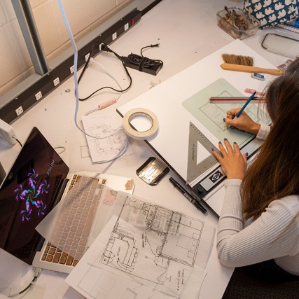 overhead view of woman working on architectural designs.