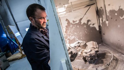 A researcher cleaning metal manufacturing parts.