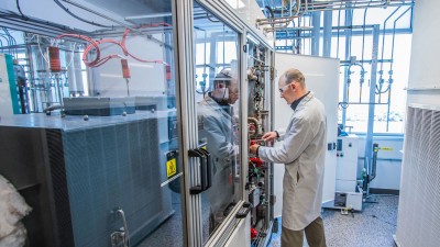 Man in lab coat working on a panel in a fuel cell lab.