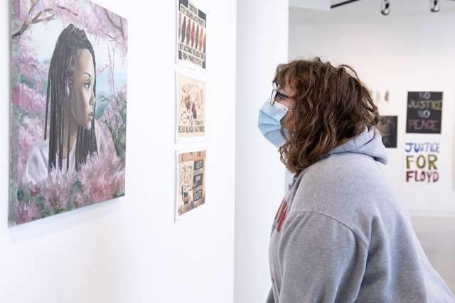 Women in a mask looking at a picture hanging on the wall