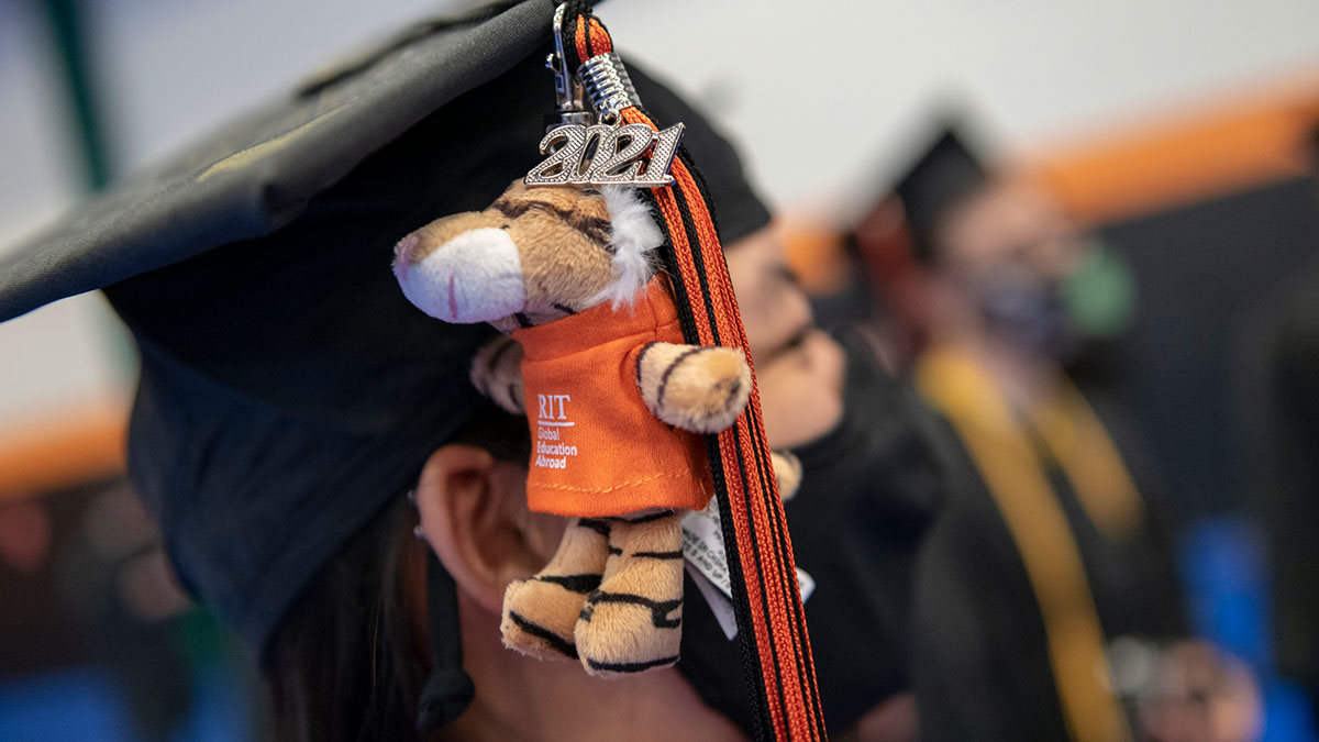 A close-up of a graduate's cap adorned with a tassel and a tiger plush with the year 20 21.