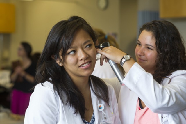 Alexandra Williams examines her partner's ear with an otoscope.