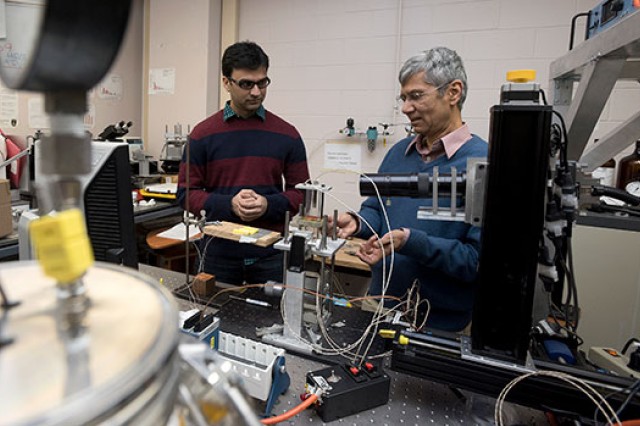 student and professor working with lab equipment.