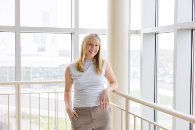 a woman with blonde hair stands in a brightly lit light atrium wearing neutral colored clothes