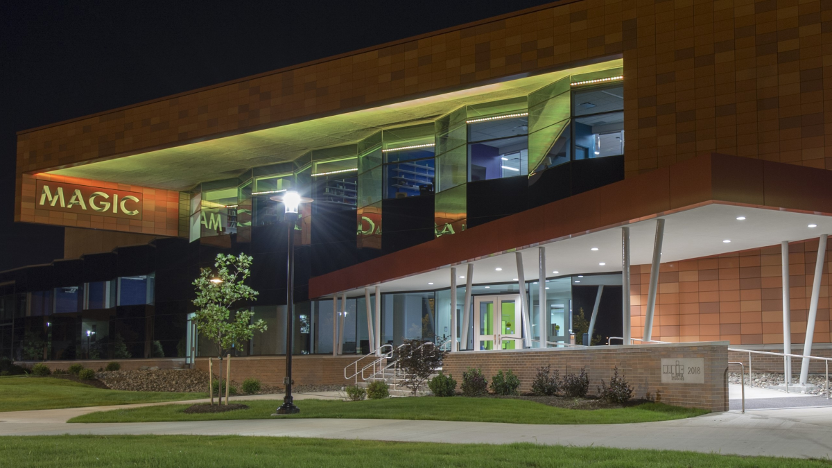 The illuminated entrance of the MAGIC building at night, showcasing modern architecture and inviting ambiance.