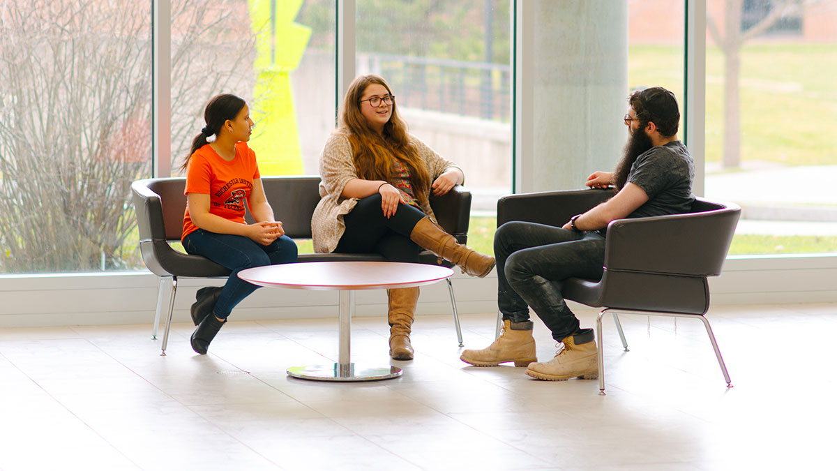 Three students conversing around a table.