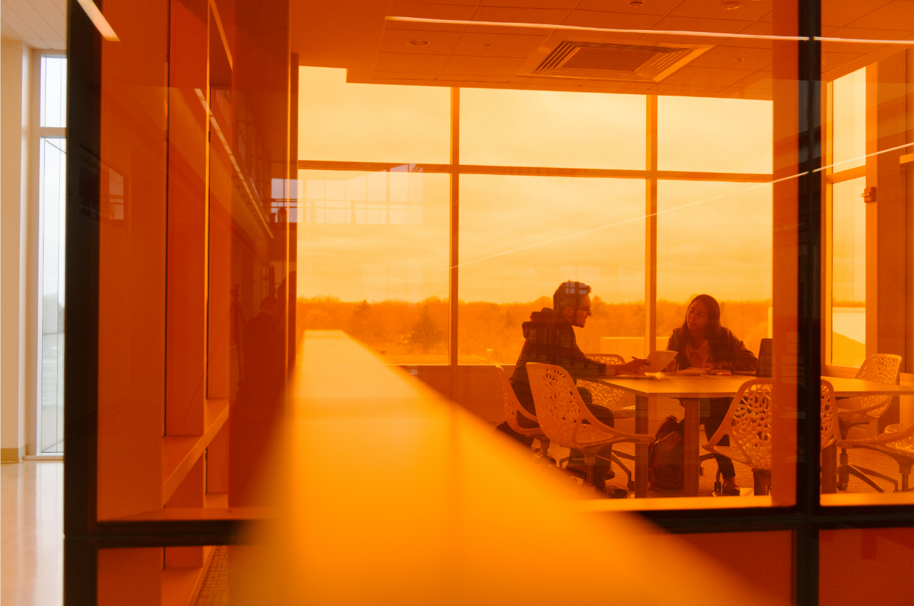 Two people working together in a conference room with windows