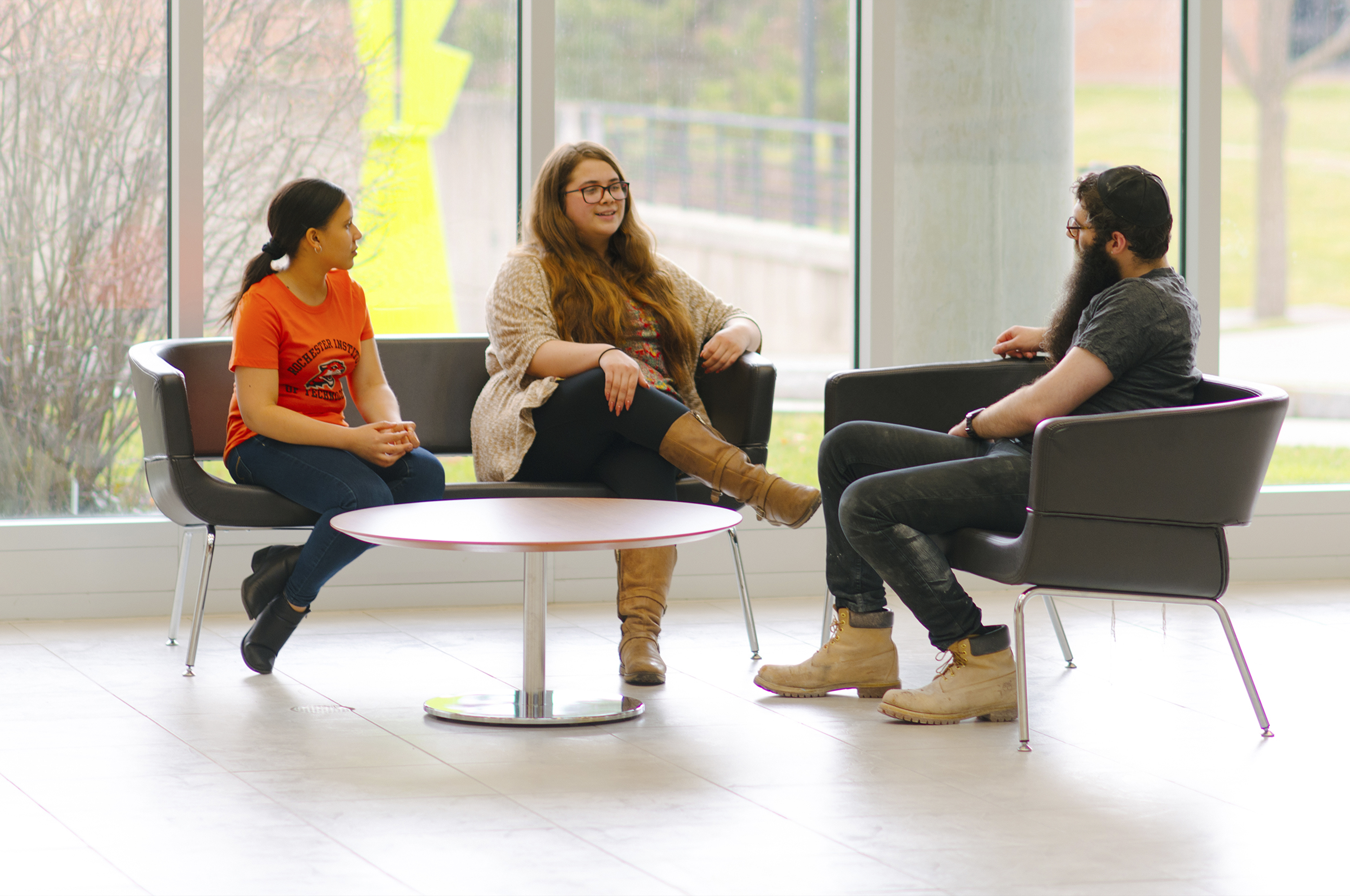 Three people sitting around a table and talking.