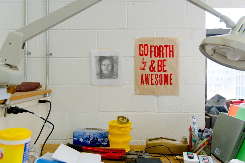 Wall with a drawing and sign that says "Go Forth & Be Awesome"