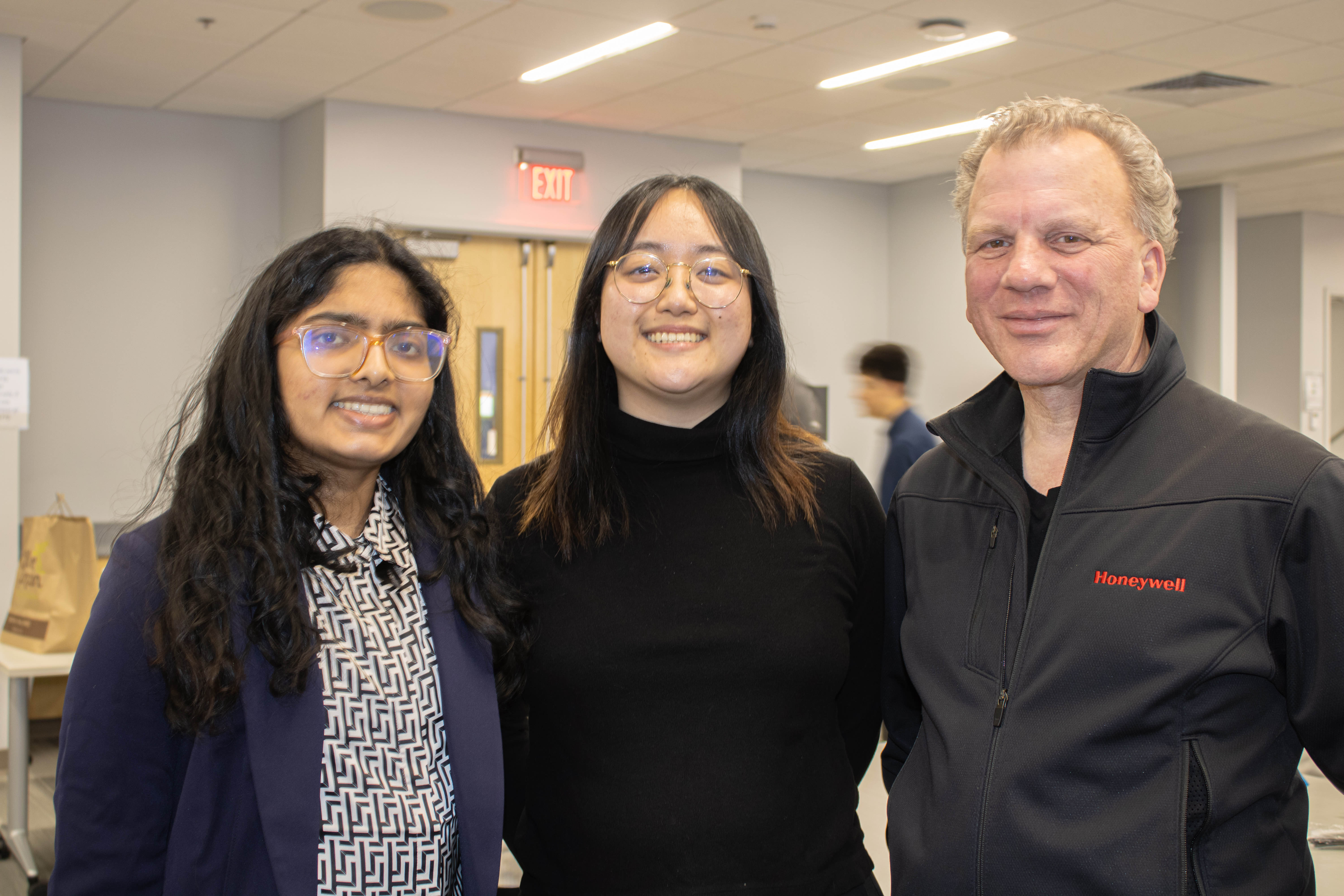 two students and an industry professional are smiling at a professional event with their arms around each other